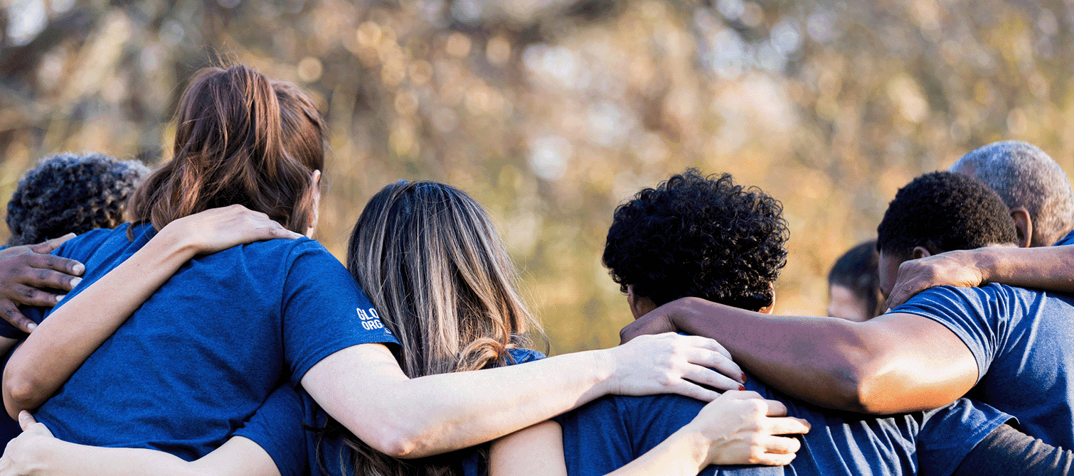 Image of a team huddled together with their arms around each other